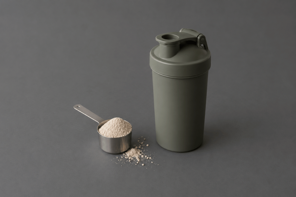 Scoopje poeder met maatschepje en onbedrukte shaker op een antracietkleurige achtergrond
